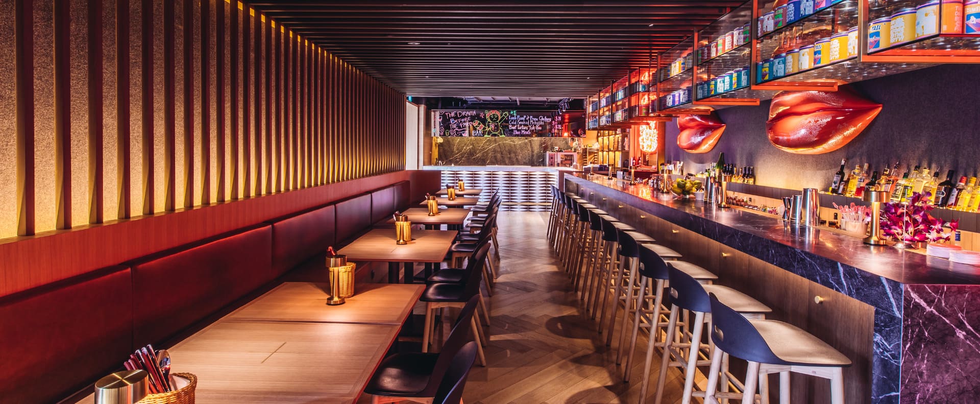 Modern restaurant bar interior with long counter seating, tables, and warm ambient lighting