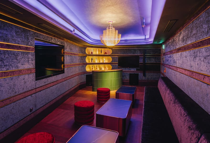 Private lounge room with bar shelves, seating, chandelier lighting, and modern decor