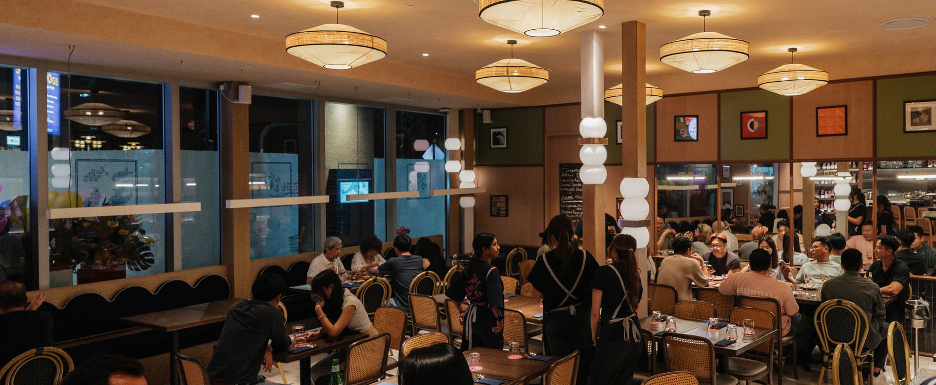 Busy restaurant interior with diners seated at tables and staff serving guests