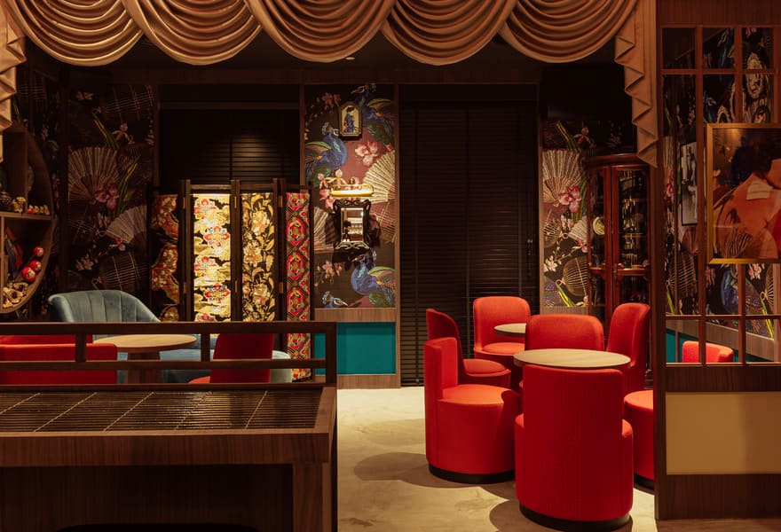 Restaurant lounge seating area with red chairs, decorative panels, and patterned wall art