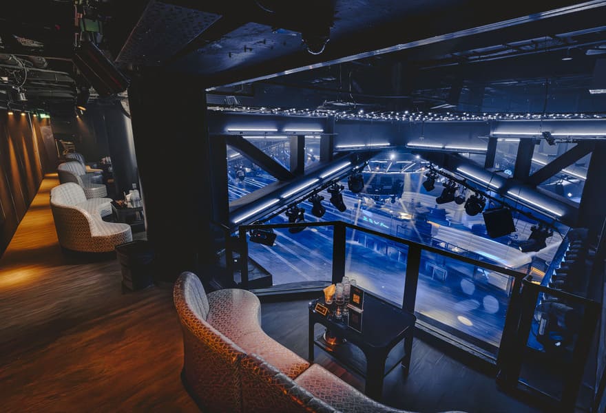 Elevated view from Zouk's VIP balcony featuring premium lounge seating overlooking the expansive dance floor, stage lighting, and main entertainment area.